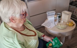 Alltagskompetenzen stärken Seniorin sitzt in der Küche und bereitet Zutaten vor