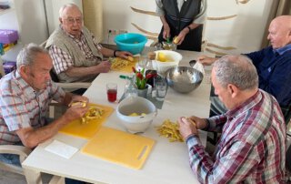 Alltagskompetenzen stärken Senioren schneiden gemeinsam Gemüse am Tisch