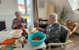 Alltagskompetenzen stärken Zwei Seniorinnen schälen Karotten und Kartoffeln am Tisch