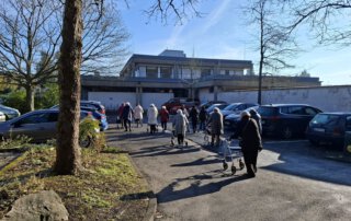 Botanischer Garten Marburg Gäste gehen bei Sonnenschein über den Parkplatz zum Botanischen Garten Marburg