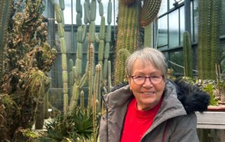 Botanischer Garten Marburg Seniorin im roten Pullover vor hohen Säulenkakteen