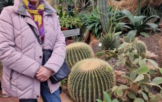 Botanischer Garten Marburg Seniorin in lila Jacke vor großen Kugelkakteen