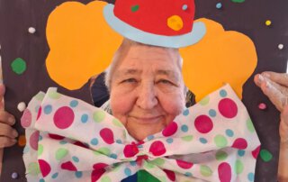 Fasching 2025 – Tanz, Musik und gute Laune Seniorin schaut lachend durch eine Clown-Fotowand