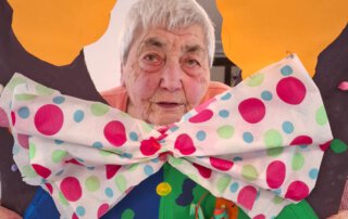 Fasching 2025 – Tanz, Musik und gute Laune Seniorin schaut durch eine Clown-Fotowand mit großer Fliege