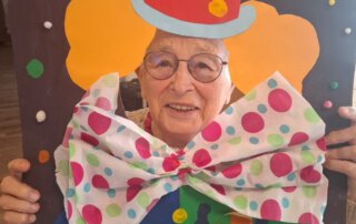 Fasching 2025 – Tanz, Musik und gute Laune Seniorin mit Brille schaut durch die Clown-Fotowand