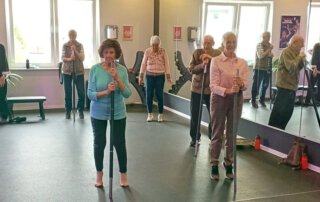Regelmäßige Besuche im Fitnessstudio Gäste machen gemeinsam Übungen vor der Spiegelwand im Kursraum