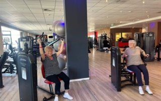Regelmäßige Besuche im Fitnessstudio Zwei Seniorinnen trainieren an Geräten im Fitnessstudio