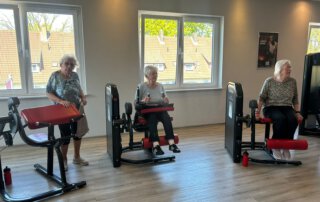 Regelmäßige Besuche im Fitnessstudio Drei Seniorinnen trainieren nebeneinander an Beingeräten