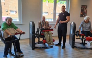 Regelmäßige Besuche im Fitnessstudio Gäste trainieren an Geräten, ein Trainer steht daneben