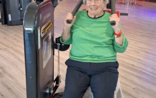 Regelmäßige Besuche im Fitnessstudio Seniorin im grünen Pullover lacht beim Training