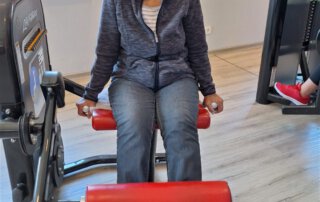Regelmäßige Besuche im Fitnessstudio Seniorin trainiert an der Beinstreckmaschine