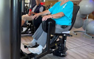 Regelmäßige Besuche im Fitnessstudio Seniorin im türkisen Shirt trainiert an einem Gerät