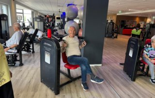 Regelmäßige Besuche im Fitnessstudio Seniorin trainiert an einem Gerät auf der großen Trainingsfläche
