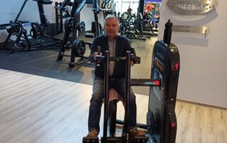 Regelmäßige Besuche im Fitnessstudio Senior trainiert an einem Gerät im Kraftbereich