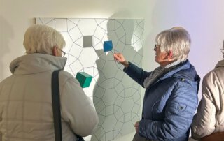 Zwei Seniorinnen probieren eine Mitmach-Station an der Wand aus