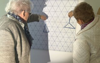 Zwei Seniorinnen knobeln an einer Wandstation im Mathematikum