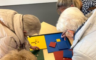 Seniorinnen lösen ein Legespiel aus bunten Formen