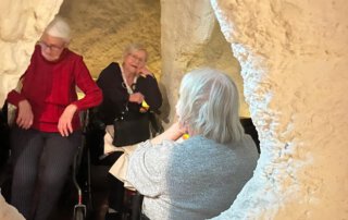 Seniorinnen sitzen gemeinsam in der Salzgrotte, eine von ihnen lacht