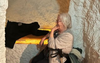 Seniorin mit Rollator sitzt lächelnd in der Salzgrotte