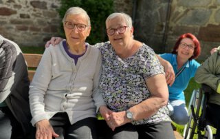 Es muss nicht immer weit sein Zwei Seniorinnen sitzen lächelnd auf einer Bank