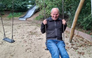 Es muss nicht immer weit sein Senior schaukelt auf dem Spielplatz