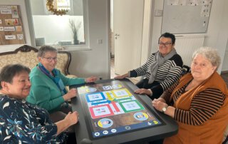 Digitalisierung zum Anfassen-Der Care Table ist da! Vier Seniorinnen spielen am Care Table ein Brettspiel