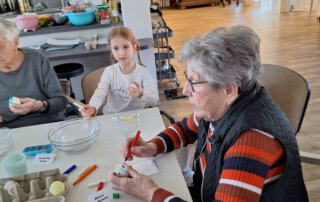 Ostereier färben mit der Kita Regenbogen Seniorin und Mädchen bemalen gemeinsam Ostereier