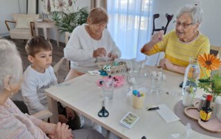 Ostereier färben mit der Kita Regenbogen Junge und Seniorinnen bemalen Eier am Tisch