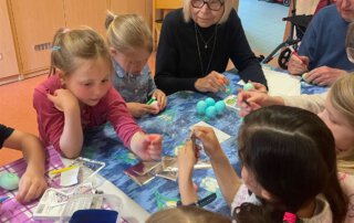 Ostereier färben mit der Kita Regenbogen Kinder und eine Seniorin färben Eier im Kindergarten