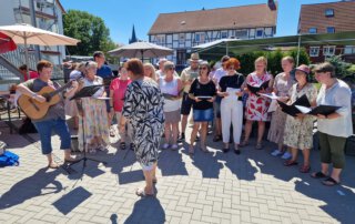Sommer, Sonne, Gemeinschaft Chor singt mit Gitarrenbegleitung auf dem Hof