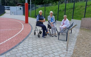 Gäste sitzen am Rand des neuen Basketballplatzes