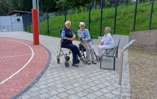 Gäste sitzen auf einer Bank neben dem Basketballkorb