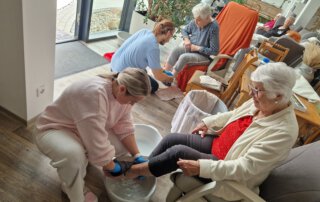 Auszubildende macht mit einer Seniorin ein Fußbad