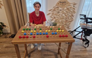 Auszubildende sitzt an einem Spielbrett mit bunten Kugeln