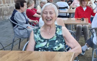 Eiswagen am Turm Seniorin lacht am Tisch vor dem Eiscafé am Turm