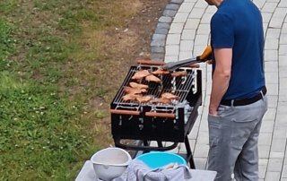 Zwei sommerliche Grillwochen mit fröhlicher Stimmung Mitarbeiter grillt im Garten des TagWerk