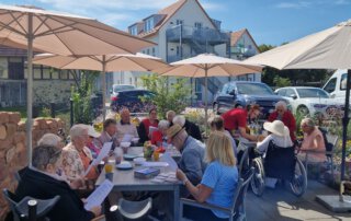 Zwei sommerliche Grillwochen mit fröhlicher Stimmung Gäste sitzen unter Sonnenschirmen auf der Terrasse