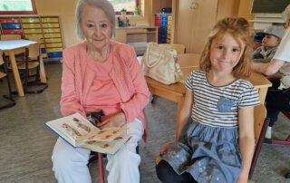 Meet and Read Seniorin und Mädchen halten gemeinsam ein Buch