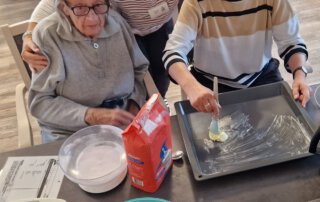 Erntedankwoche 2025 Zwei Seniorinnen und eine Mitarbeiterin bereiten einen Kuchen vor