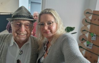 O`zapft is… Senior mit Trachtenhut und Mitarbeiterin machen ein Selfie