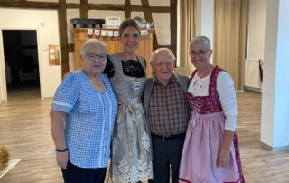 O`zapft is… Vier Personen in Tracht stehen zusammen